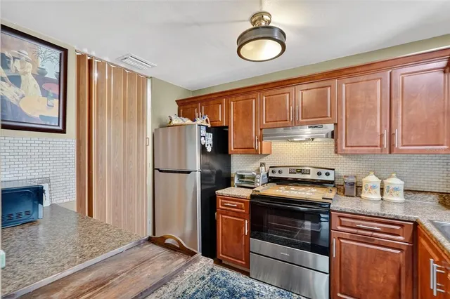 a kitchen with stainless steel appliances granite countertop a refrigerator stove top oven and sink