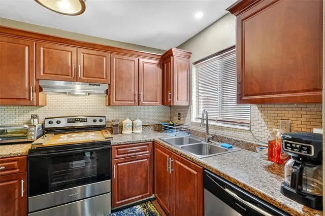 a kitchen with stainless steel appliances granite countertop a sink stove and cabinets