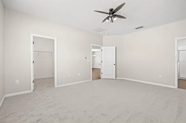an empty room with chandelier fan and closet