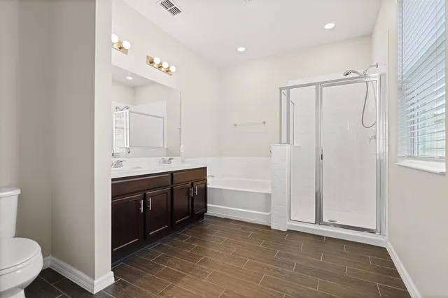 a bathroom with a double vanity sink a toilet a mirror and shower