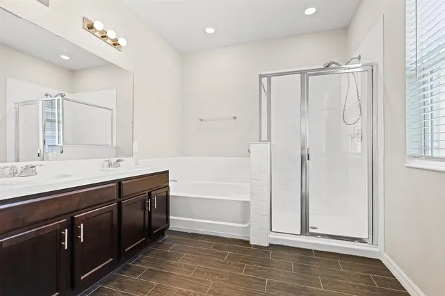 a bathroom with a double vanity sink a large mirror and a bathtub