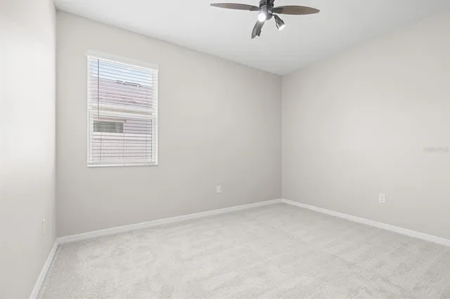 an empty room with a ceiling fan and window
