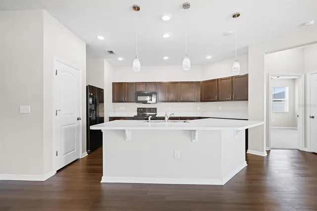 a view of a kitchen with stainless steel appliances wooden floor and living room view