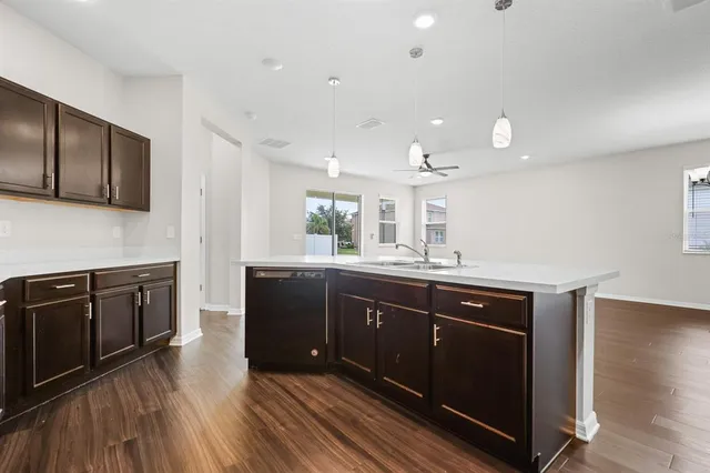 a kitchen with stainless steel appliances granite countertop wooden cabinets a sink dishwasher a stove and a refrigerator with wooden floor