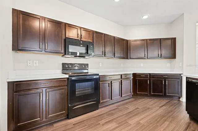 a kitchen with granite countertop wooden cabinets stainless steel appliances and a wooden floor