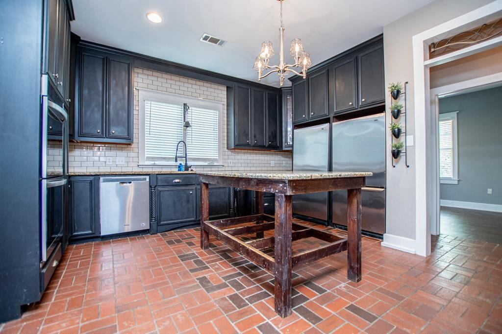 75 Cash Lane Bremen, GA 30110 - Photo 28 of 92 a kitchen with stainless steel appliances granite countertop a stove top oven a sink dishwasher a dining table and chairs with wooden floor