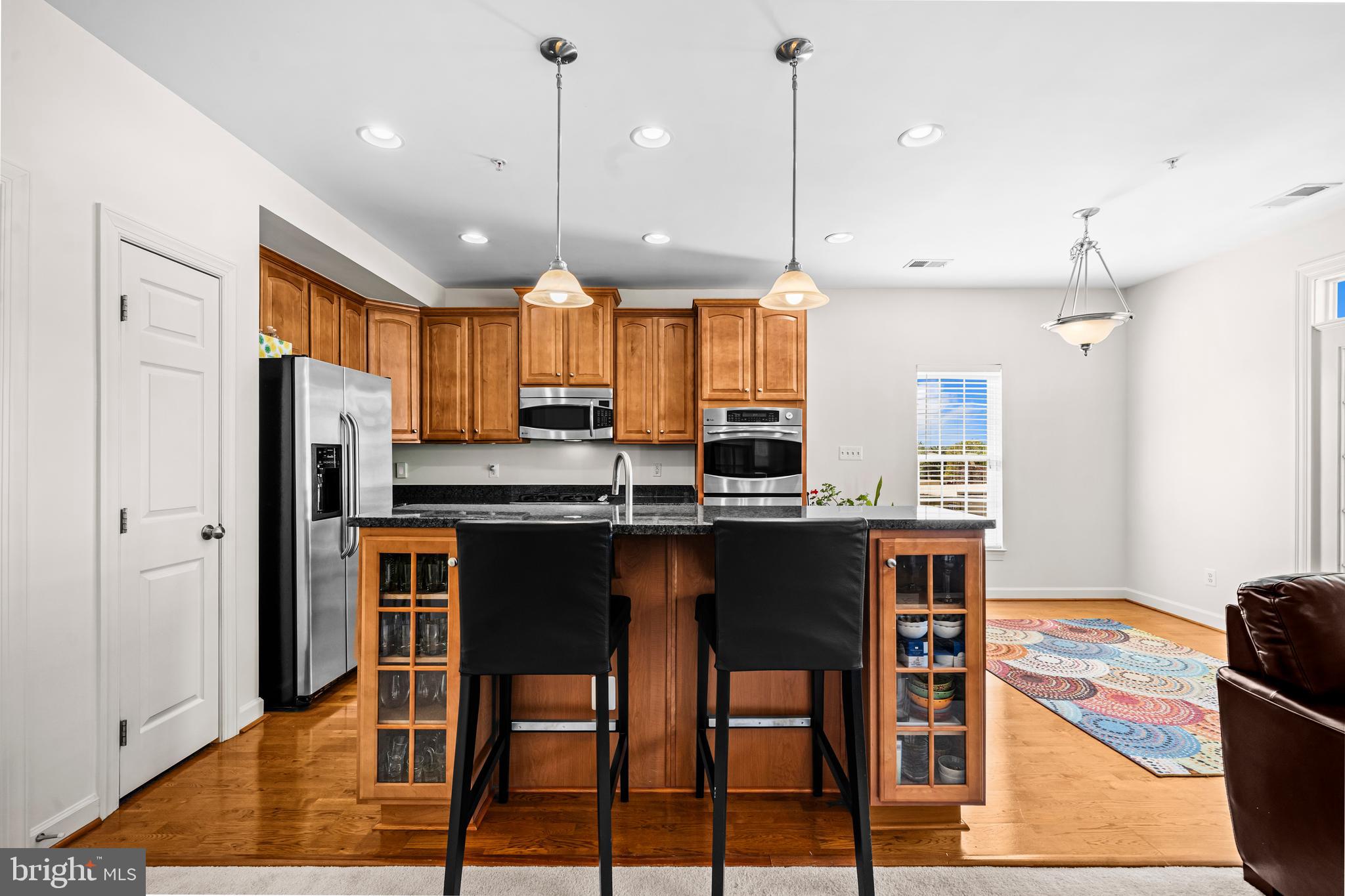 5725 Callcott Way, Unit P Alexandria, VA 22312 - Photo 13 of 40 a kitchen with stainless steel appliances kitchen island granite countertop a table chairs refrigerator and microwave