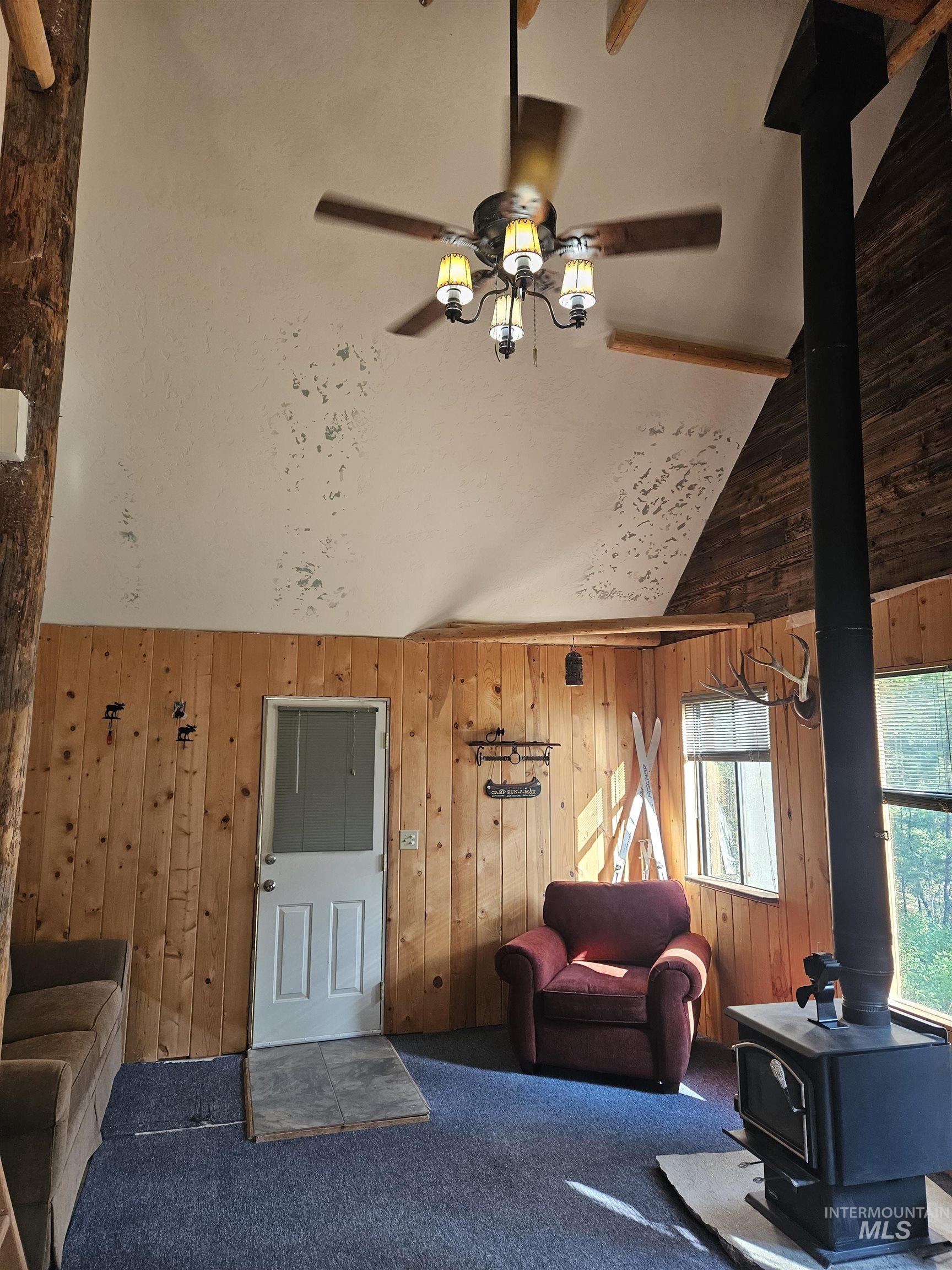 1510 Crown Point Parkway Cascade, ID 83611 - Photo 14 of 19 Carpeted living area with a wood stove, high vaulted ceiling, and wooden walls