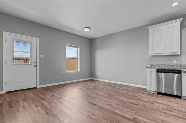 a view of an empty room with a window and wooden floor