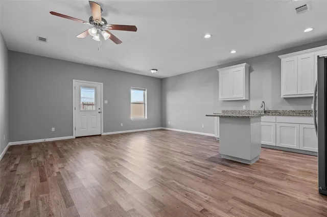 a view of an empty room with a window and wooden floor