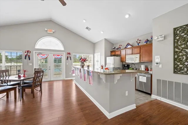 a very nice looking open dining room with kitchen island wooden floor and stainless steel appliances
