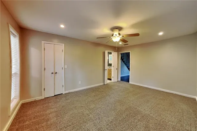 an empty room with closet and a ceiling fan