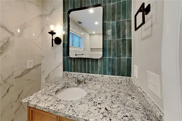 a bathroom with a granite countertop sink a toilet and a mirror