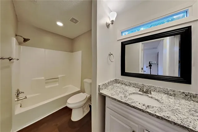 a bathroom with a granite countertop toilet sink and a bathtub