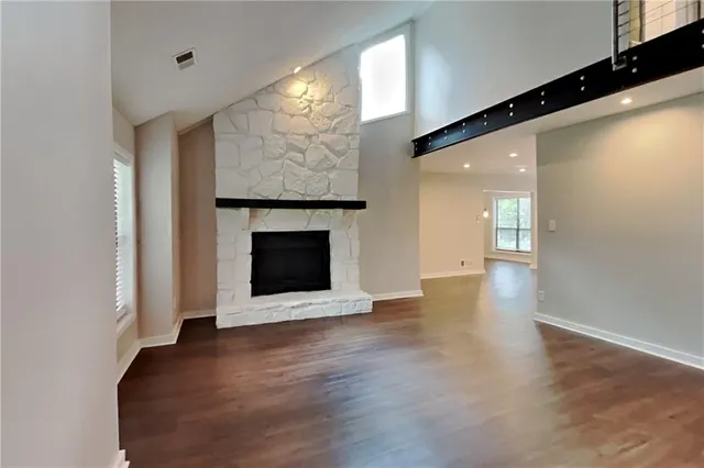 a view of an empty room with wooden floor and a fireplace