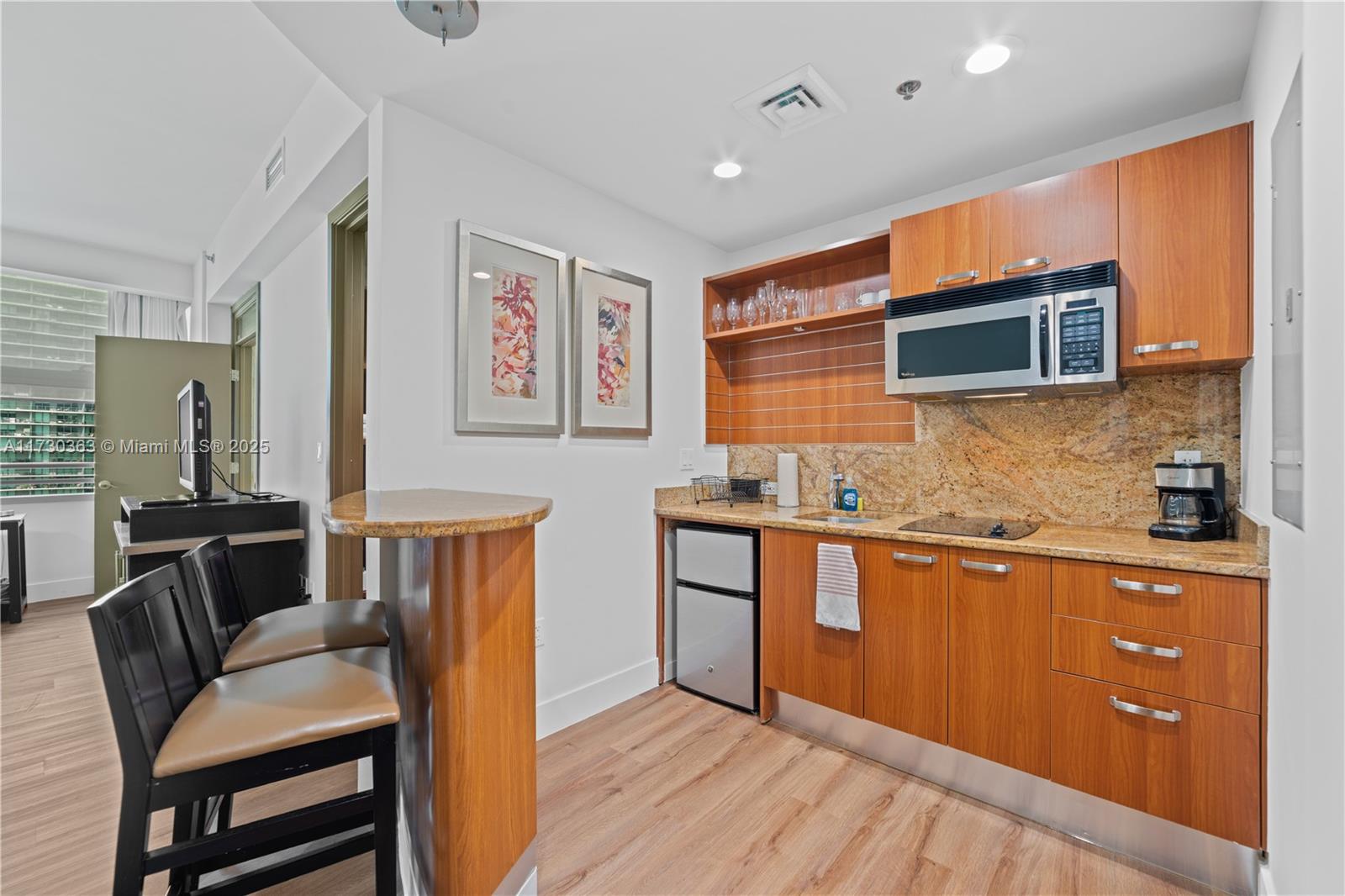 Brickell Miami, FL 33131 - Photo 16 of 19 a kitchen with granite countertop cabinets a sink a stove a dining table and chairs