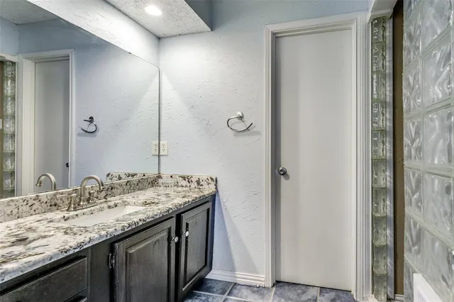 a bathroom with a granite countertop sink and a mirror