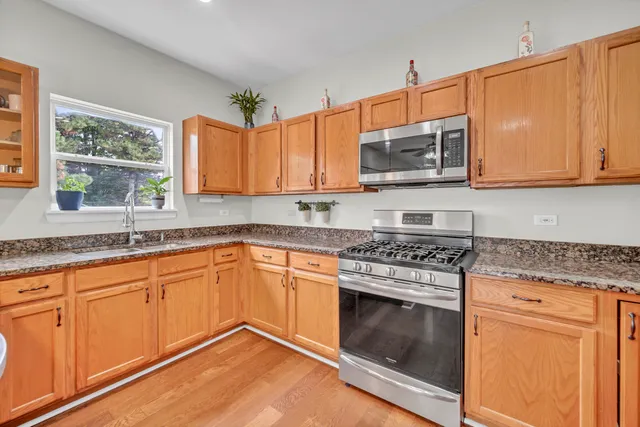 a kitchen with granite countertop a sink cabinets stainless steel appliances and a window