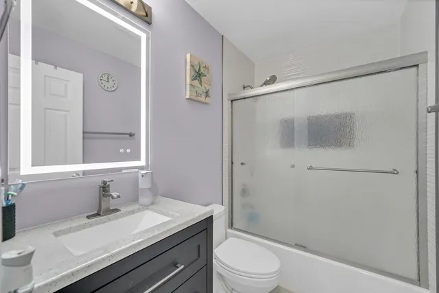 a bathroom with a granite countertop sink toilet a mirror and shower