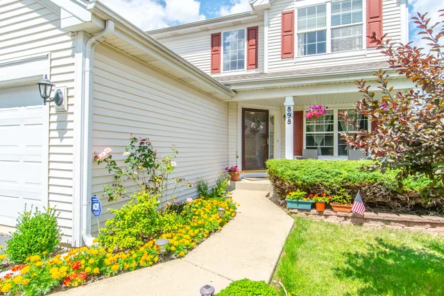 a front view of a house with a yard and potted plants