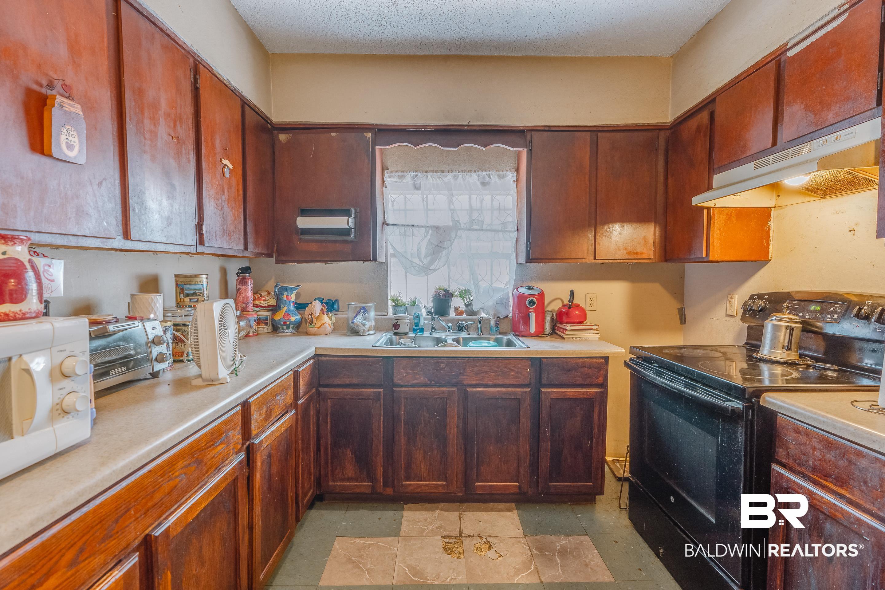 1156 Freeman Street Mobile, AL 36605 - Photo 8 of 22 Kitchen featuring a sink, black range with electric stovetop, white microwave, under cabinet range hood, and light countertops