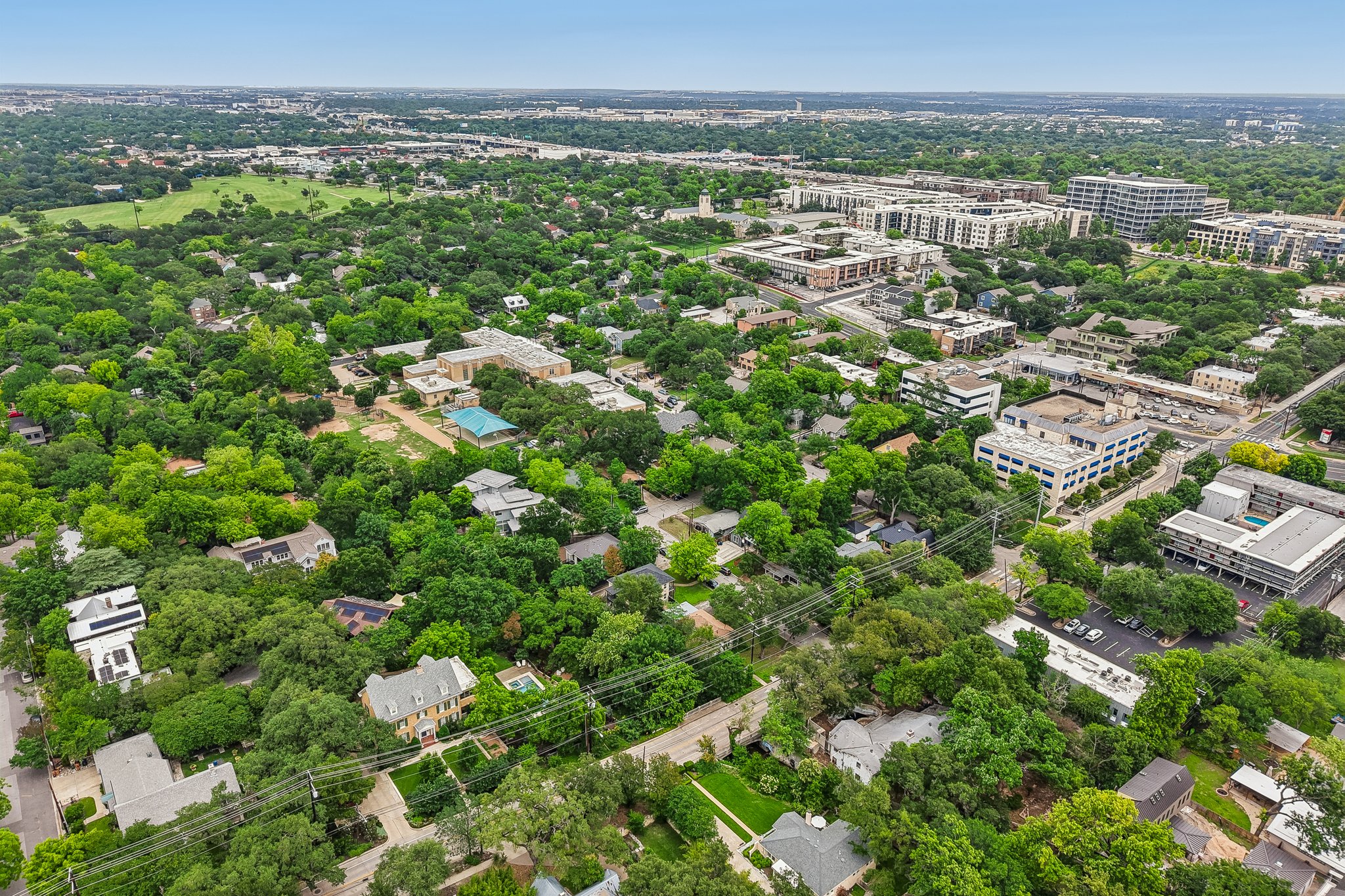 801 East 32nd Street Austin, TX 78705 - Photo 6 of 13 An aerial panorama reveals a verdant neighborhood with residential homes nestled amidst mature trees and urban structures.