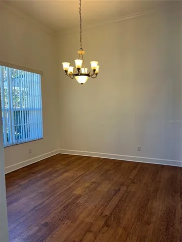an empty room with wooden floor chandelier fan and windows