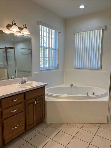 a spacious bathroom with a tub sink and mirror