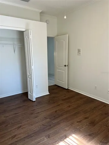 a view of an empty room with wooden floor and closet