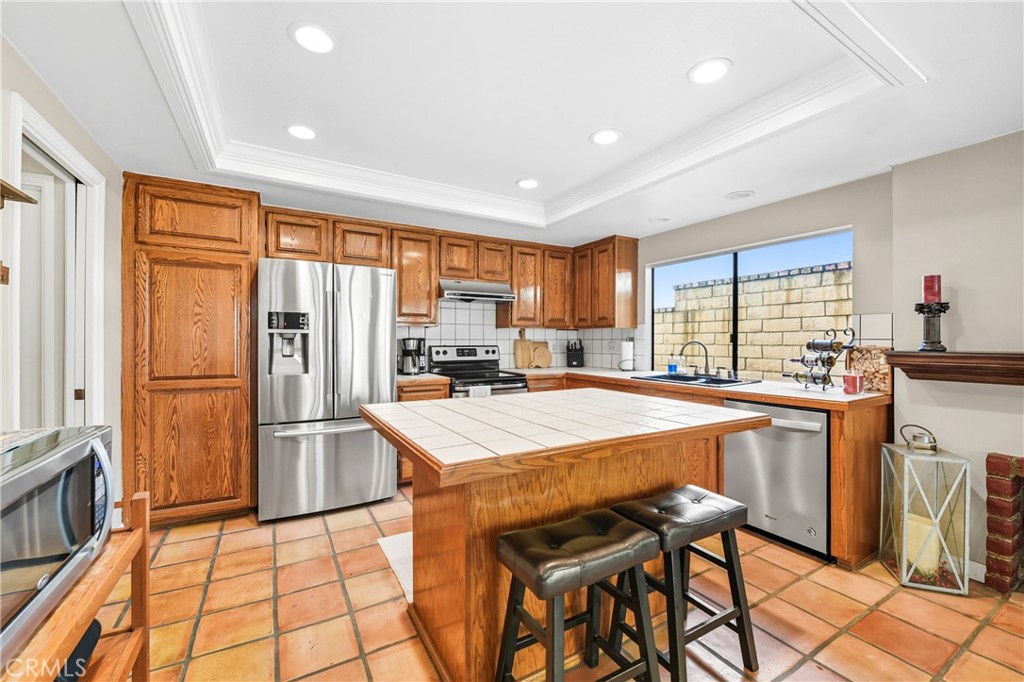 21902-21902 Raintree Lane Lake Forest, CA 92630 - Photo 12 of 46 a kitchen with granite countertop a refrigerator a stove a sink dishwasher and white cabinets with wooden floor