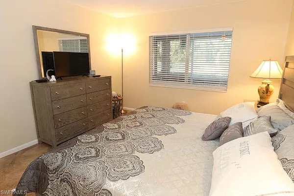 a bedroom with a bed flat screen tv and a window