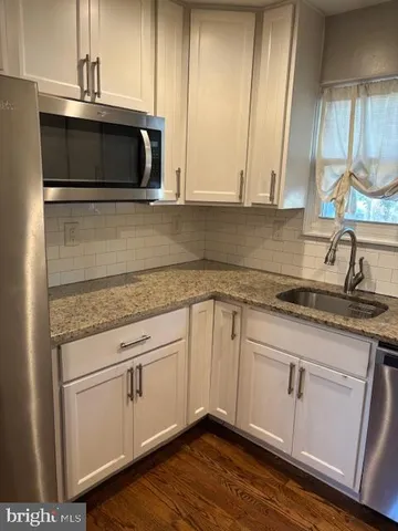 a kitchen with granite countertop white cabinets and a sink