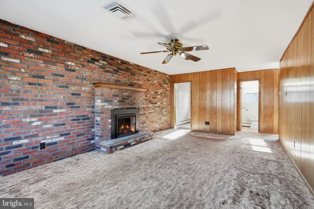 a view of an empty room with a fireplace and a fan