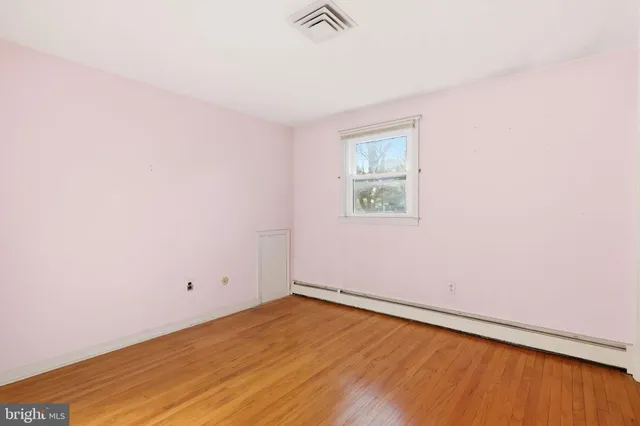 an empty room with a window and wooden floor