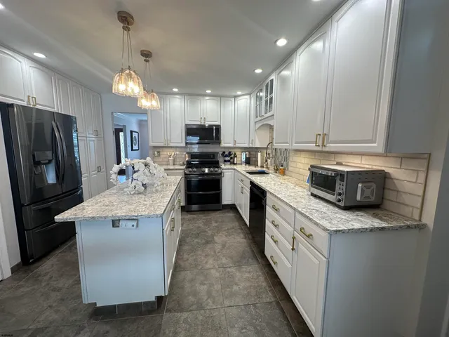 a kitchen with stainless steel appliances granite countertop a sink stove refrigerator and cabinets
