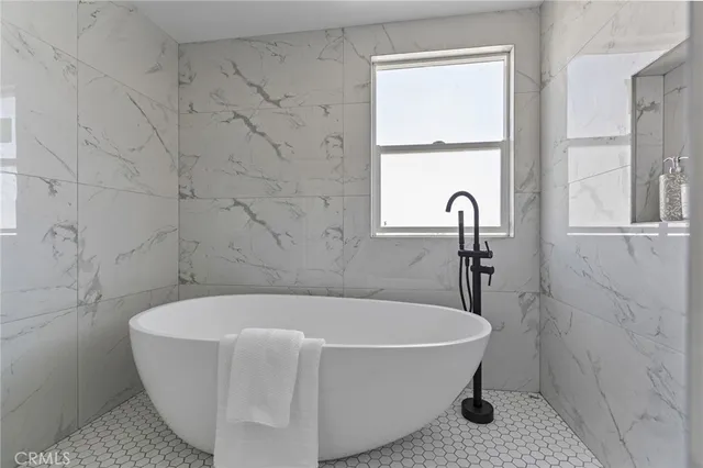 a white bath tub sitting in a bathroom next to a window