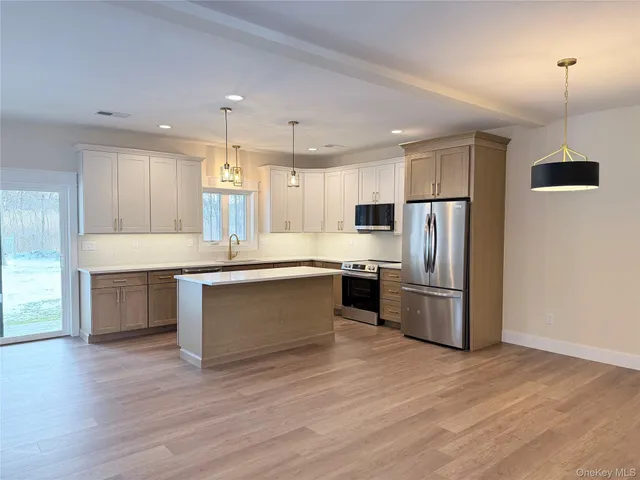 a kitchen with kitchen island granite countertop a stove a sink and a microwave