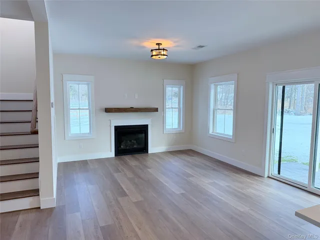 an empty room with wooden floor fireplace and windows