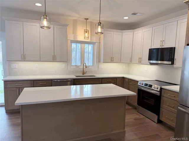 a view of a kitchen with kitchen island a sink wooden floor and a refrigerator