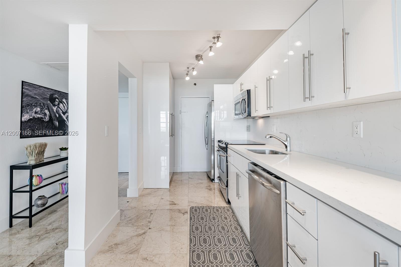 100 Lincoln Road, Unit 944 Miami Beach, FL 33139 - Photo 9 of 40 a kitchen with a sink dishwasher and white cabinets