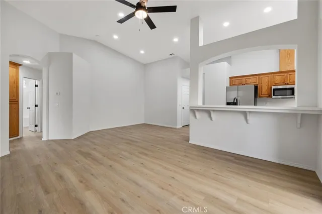 an empty room with a kitchen and chandelier fan