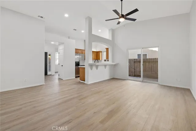 an empty room with wooden floor and a kitchen