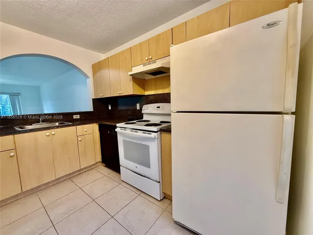 a white refrigerator freezer and a stove sitting inside of a kitchen