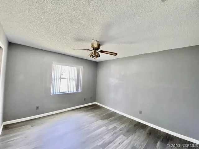an empty room with wooden floor fan and windows