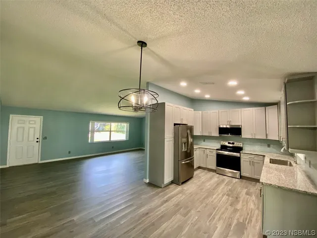 a kitchen with stainless steel appliances granite countertop a refrigerator a stove oven a sink dishwasher and a wooden cabinets with wooden floor