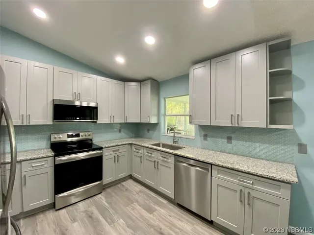 a kitchen with granite countertop white cabinets and stainless steel appliances