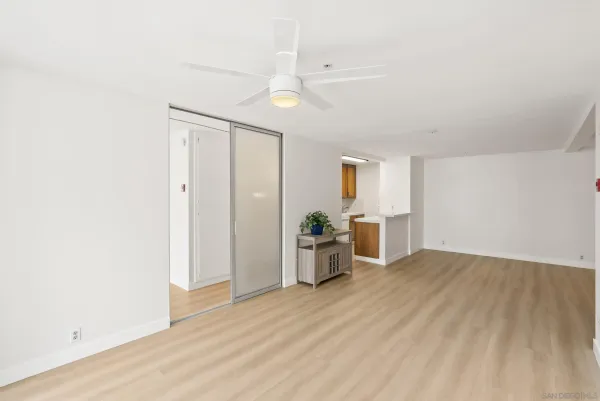 a view of empty room with wooden floor and fan