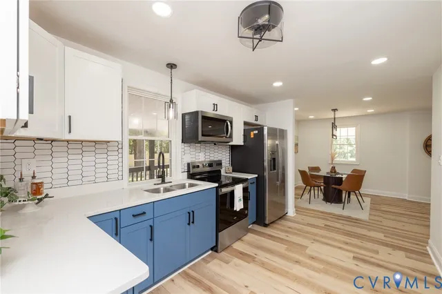 a kitchen with stainless steel appliances granite countertop a sink dishwasher a stove and a refrigerator with wooden floor