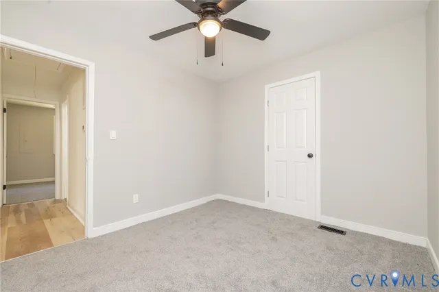 an empty room with a ceiling fan and a window