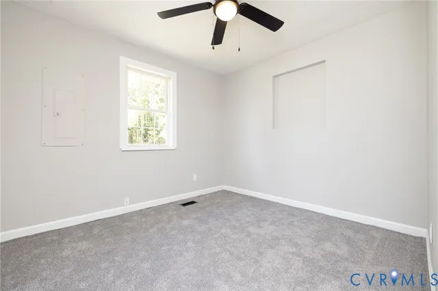 an empty room with ceiling fan and window